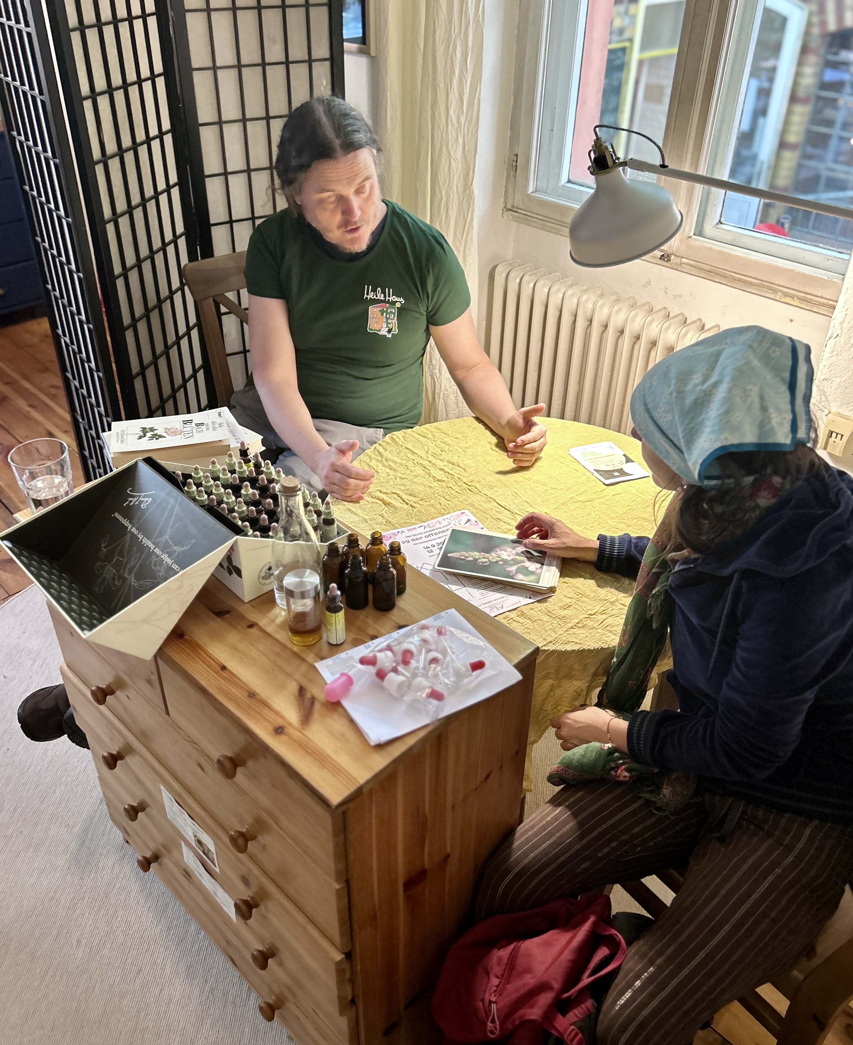 Zwei Personen sitzen an einem Tisch mit Bachblütengläschen und einem Notizblock