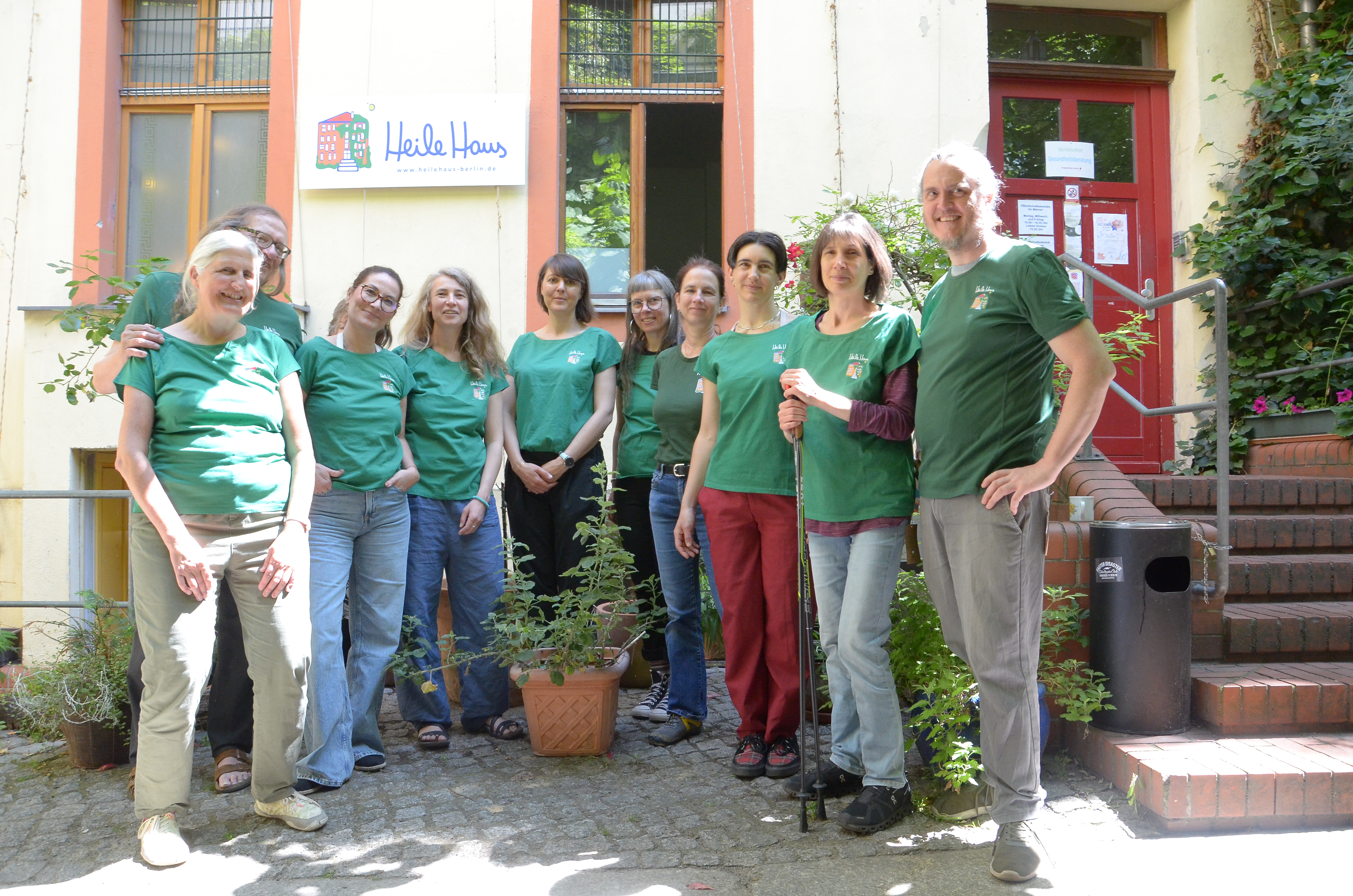 Das Team der Gesundheitsberatung steht im Halbkreis vor dem HeileHaus