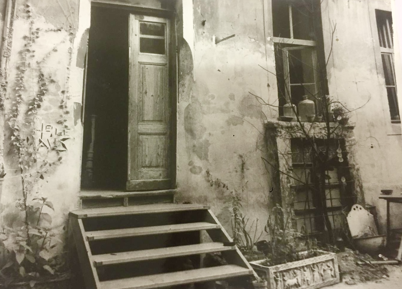 Historisches Schwarz-Weiß-Foto: altes heruntergekommenes Gebäude mit Stufen aus Holz, die zur Eingangstür führen.